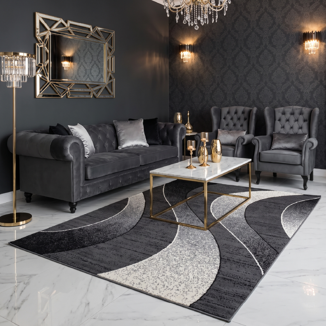 elegancki salon w ciemniejszej palecie: dywan w głębokiej szarości. Meble tapicerowane, metalowe akcesoria